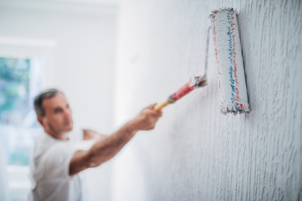 Ein Maler streicht eine weiße Wand | Stellenangebot Maler*in und Lackierer*in bei der CMS Bautechnik GmbH